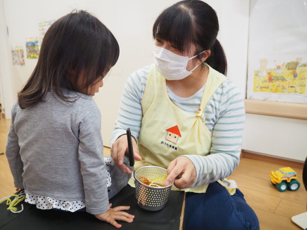 ままごとをする園児と保育士