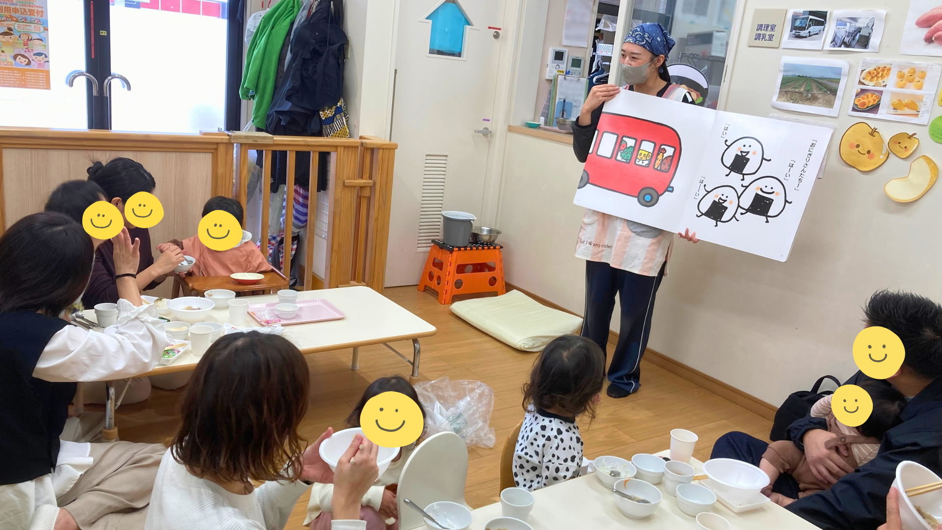 園行事（芋煮会）の様子。親子で芋煮を食べながら、保育士の読み聞かせを聞いている。